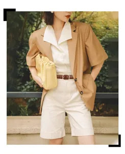 Detail of a vintage brown leather belt with a gold pin buckle on a casual summer outfit.