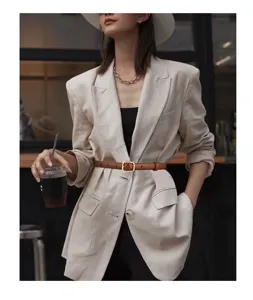 Detail view of a slim retro brown leather belt with gold pin buckle on a beige blazer