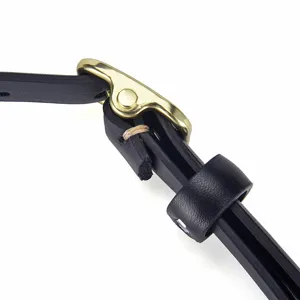 Close-up detail of a minimalist slim black leather belt with a polished gold pin buckle