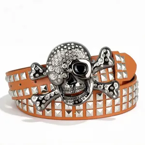 Ceinture en cuir orange style punk avec clous pyramidaux et boucle tête de mort strassée.