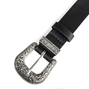 Detailed close-up of ornate silver Western-style buckle on a vintage black leather belt