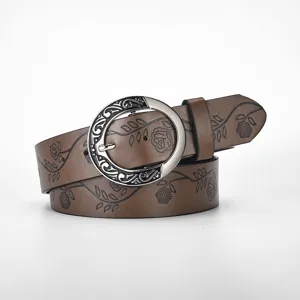 Detail view of retro brown leather belt with floral embossing and silver carved buckle