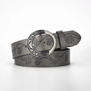 Close-up detail of retro wide leather belt featuring intricate floral patterns and round buckle