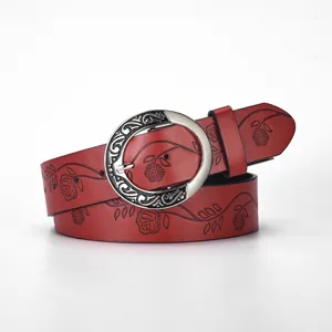 Close-up of vintage red leather belt featuring intricate floral embossing and silver buckle