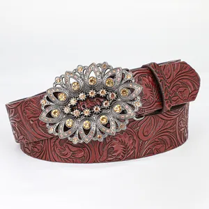 Detailed macro view of retro embossed floral pattern on leather belt with ornate rhinestone buckle