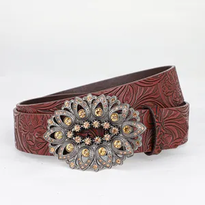 Detailed view of vintage brown leather belt with floral embossing and ornate rhinestone buckle