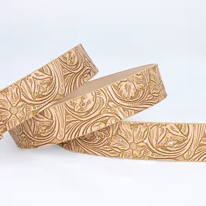 Macro view of vintage floral embossed pattern on a light tan leather belt detail.