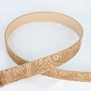 Detailed view of a vintage tan belt featuring an intricate floral embossed pattern