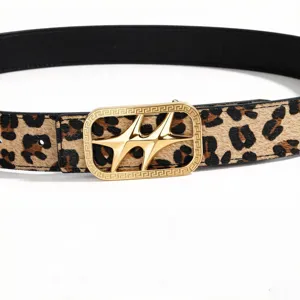 Detalle de cinturón reversible con estampado de leopardo y hebilla de estrella dorada.