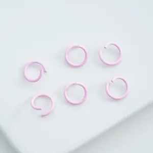 Detailed macro view of small pink matte coated alloy open jump rings for jewelry DIY.