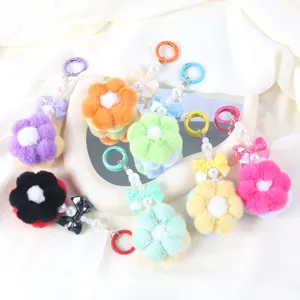 Various colorful plush flower keychains with beaded chains and bow charms on white display