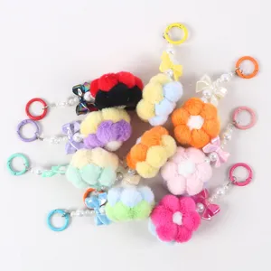 Macro view of colorful handmade plush flower keychains with pearl beads and bows.