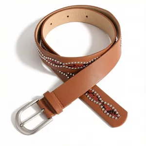 Close-up of brown leather belt for women with rhinestone studs and metal buckle.