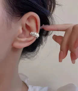 Close-up view of a silver double-layer ear cuff with sparkling zircons worn on ear.