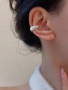 Detailed close-up of a stylish double-layered silver zircon ear cuff on a model's ear
