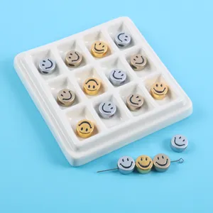 Detailed view of gold and silver metallic smiley face beads in a white display tray