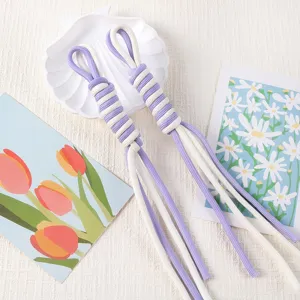 Detail view of hand-woven purple and white Roman knot lanyards on decorative props.
