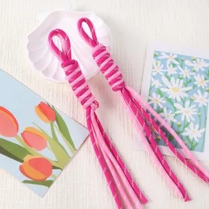 Macro detail shot of two pink handmade braided lanyards with decorative Roman knot patterns
