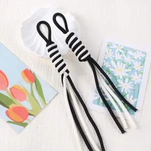 Close-up detail of black and white handmade woven Roman knot lanyards for DIY accessories