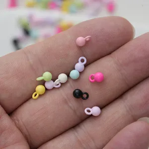 Close-up van macaron gekleurde metalen kraalhangers in een hand voor DIY-sieraden