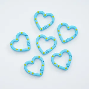 Close-up of blue heart-shaped spring snap hooks with yellow dots for DIY jewelry.