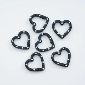 Detailed view of black heart spring clasps with white polka dots for custom jewelry making.