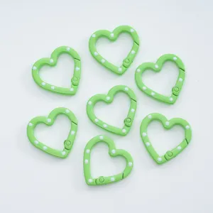 Detailed view of green heart-shaped spring clasps with white dots, perfect DIY jewelry making.