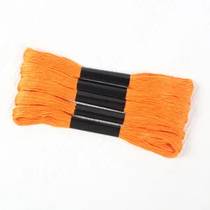Close-up detail of five bundles of bright orange 6-strand embroidery thread on white background