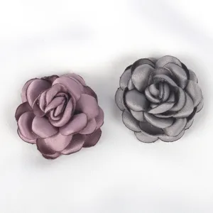 Detailed view of handmade satin roses with singed petals for DIY jewelry making