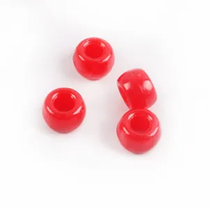 Gros plan de perles barils en acrylique rouge, grandes perles pour la fabrication de bijoux.
