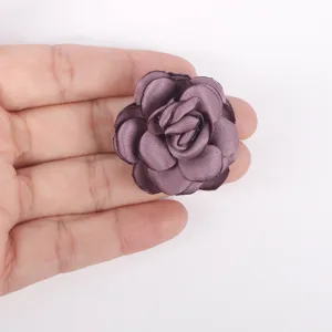Detailed view of a handmade burned-edge satin rose flower held in hand for scale
