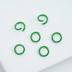 Close-up of green painted alloy open jump rings for DIY jewelry making crafts.