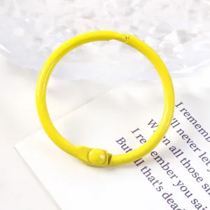 Primer plano de una anilla de metal lacado amarillo de 30 mm para proyectos de encuadernación.