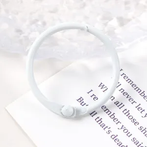 Detalle de una anilla de encuadernación blanca de 30mm para llaveros DIY y hojas sueltas