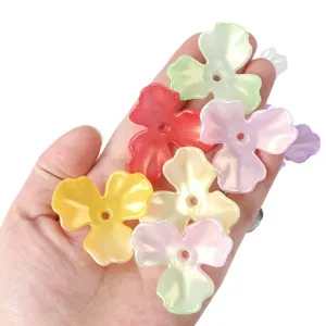 Hand holding colorful iridescent AB acrylic magnolia flower petals for DIY jewelry making