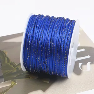 Detailed close-up of royal blue jade cord with gold glitter thread, wound neatly on spool.