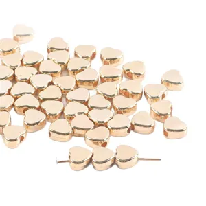Detail shot of shiny gold heart-shaped spacer beads, perfect for DIY jewelry making.