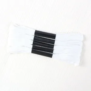 Detail view of five bundles of high-quality white embroidery floss with black paper sleeves