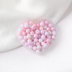 Close-up detail of glossy pink AB acrylic round craft beads inside a heart tray.