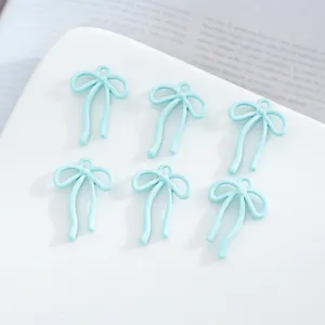 Gros plan de pendentifs nœud ruban en alliage bleu clair, idéaux pour bijoux DIY.