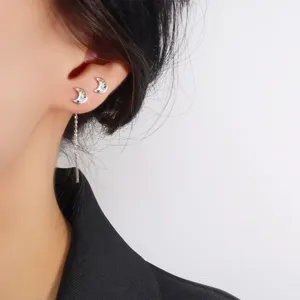 Close-up view of a colorful zircon crescent moon earring with a delicate long silver tassel.