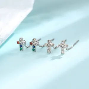 Détail de boucles d'oreilles croix en argent avec zircons colorés et blancs.