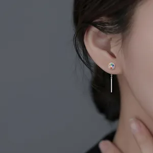 Gros plan d'une boucle d'oreille en zircon arc-en-ciel avec pompon en argent