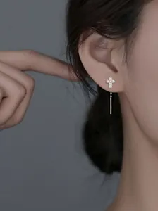Gros plan d'une boucle d'oreille croix en argent avec des oxydes de zirconium