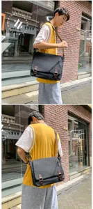 Casual black canvas messenger bag for men shown on model in urban street setting.