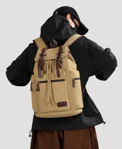 Khaki canvas travel backpack shown on a model against a clean light grey background