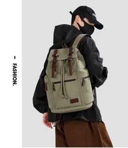 Outdoor lifestyle shot of a green canvas backpack with vintage leather straps on a model