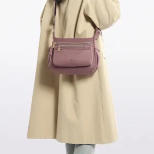 Mauve multi-pocket crossbody bag styled with a classic beige trench coat for women