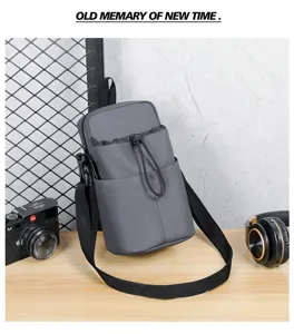 Grey waterproof crossbody bottle bag with adjustable strap in lifestyle setting.
