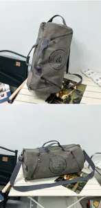 Large gray canvas duffel bag for travel and gym shown on a folding camping table